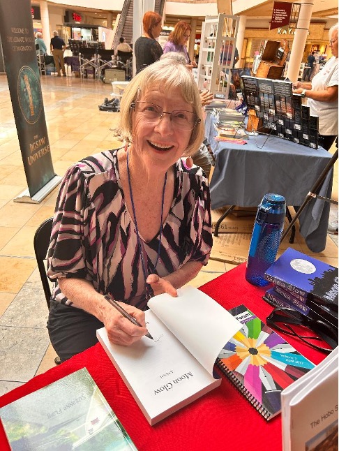 Author Sandra Rose Simmons signing a copy of her novel at the 2024 Mesa Mall Book Fest in Mesa, Arizona